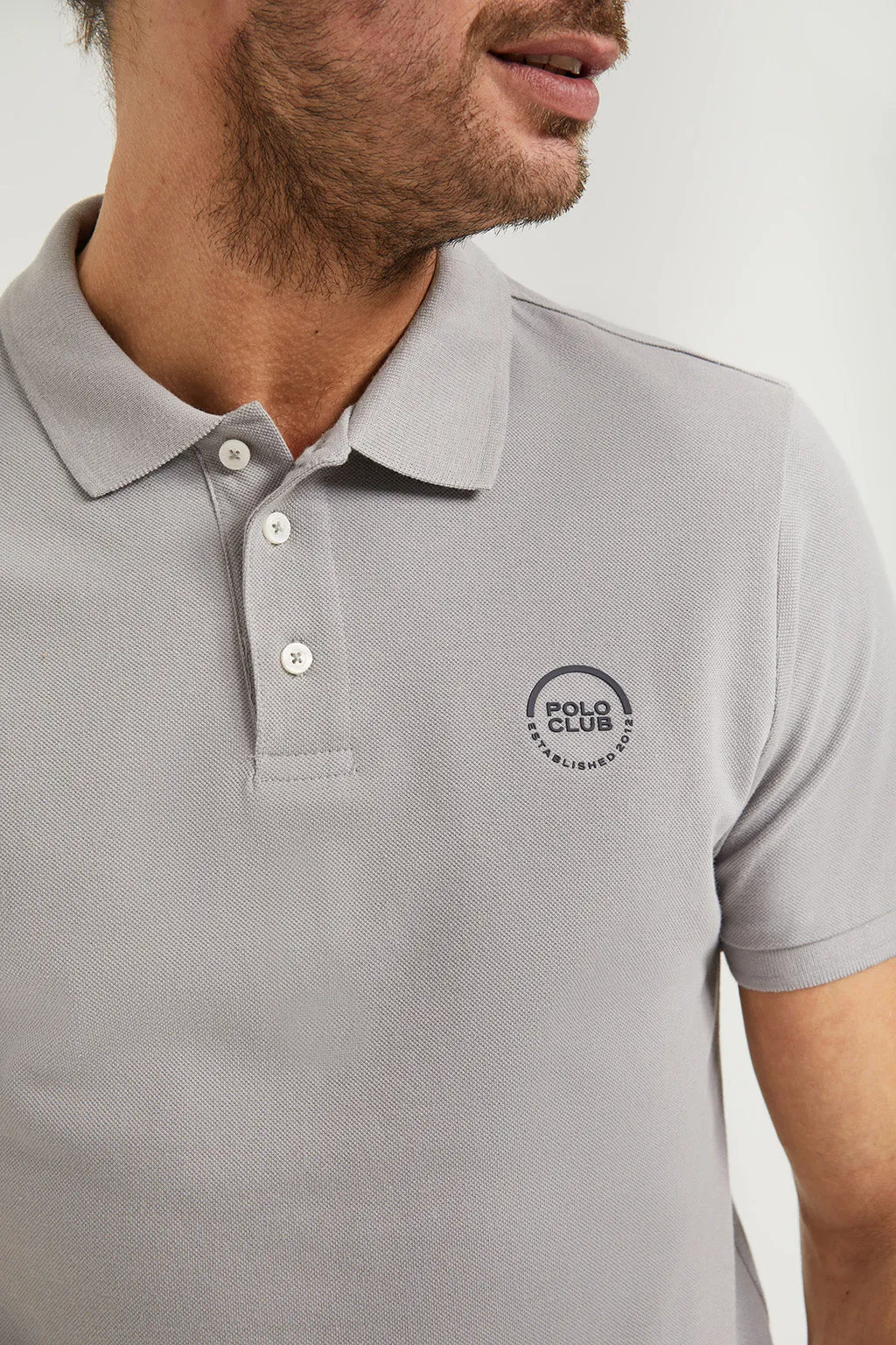 Polo gris piqué con tapeta de tres botones y logo engomado