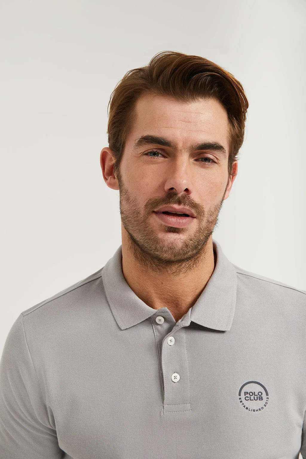 Polo gris piqué con tapeta de tres botones y logo engomado